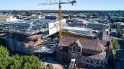 A heritage building in the foreground, yellow crane in the centre.  A new contemporary building is to the left  